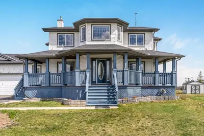 a large house with a blue front porch at Acreage, 5 bdrm, King Bed, AC, Wood Fireplace, Rural in Balzac