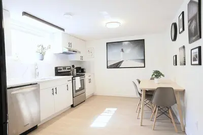 a kitchen with white cabinets and a table with chairs at Quiet Family Friendly, 4 min UofC and University District Shops, 9 min DT in Calgary