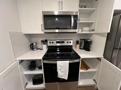 a kitchen with a stove and a microwave at Deluxe 2-Bedroom Getaway Near Calgary Airport Sleeps Up to 6 in Calgary