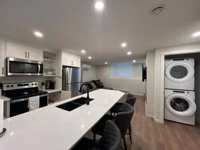 a kitchen with a white counter and a washer and dryer at Deluxe 2-Bedroom Getaway Near Calgary Airport Sleeps Up to 6 in Calgary