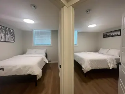 two beds in a room with two windows at Deluxe 2-Bedroom Getaway Near Calgary Airport Sleeps Up to 6 in Calgary