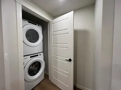 a white laundry room with a washer and dryer at Deluxe 2-Bedroom Getaway Near Calgary Airport Sleeps Up to 6 in Calgary