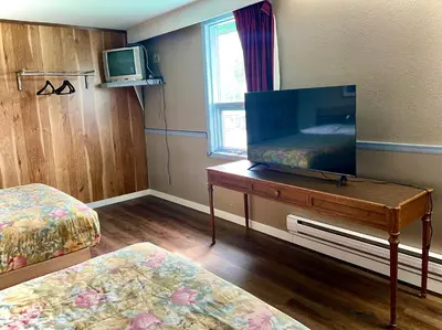a room with a tv and a bed and a table with a television at Valemount Hotel in Valemount