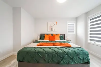 a bedroom with a large bed with orange pillows at ExoticLUSHquietRetreatKingBed|WIFI|Parking|WEM in Edmonton