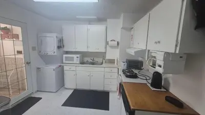 a kitchen with white cabinets and a wooden table at The Peaceful Pines in Terrace