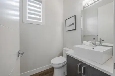 a white bathroom with a toilet and a sink at Home Theater with AC, Dual Master Suites, BBQ in Calgary