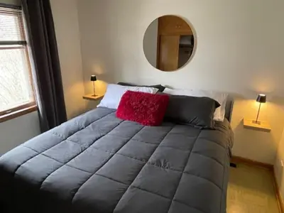 a bedroom with a large bed with a red pillow at Merlot House in Calgary