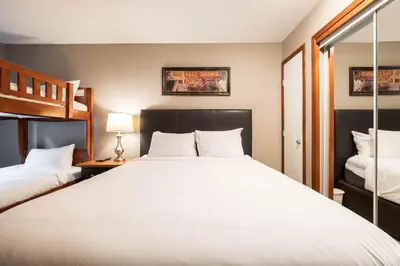 a bedroom with a large white bed and a mirror at Aspens Lodge 220 by Outpost Whistler in Whistler