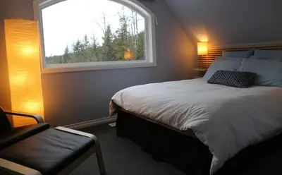 a bedroom with a bed with a window and a chair at Silver Star Bed and Breakfast in Vernon