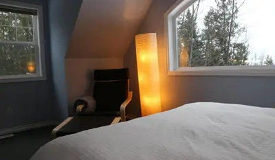 a bedroom with a bed and a chair and a window at Silver Star Bed and Breakfast in Vernon