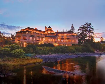 a large house on a hill next to a river at Painter's Lodge in Campbell River