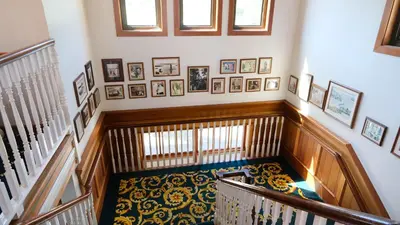 a hallway with a staircase with pictures on the wall at Painter's Lodge in Campbell River