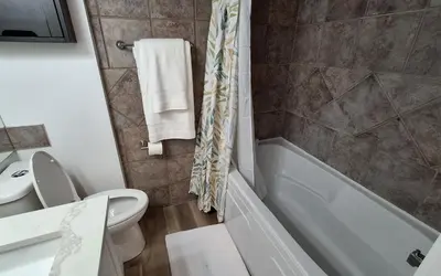 a bathroom with a toilet and a tub and a sink at Modern 1br Apt, Up to 4 people, Steps to 17th Ave, Downtown & Stampede in Calgary