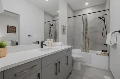 a white bathroom with a toilet and a shower at Upper and Lower, Great for Large Families, Fenced Yard in Calgary