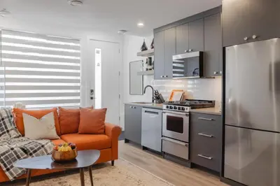 a living room with an orange couch and a kitchen at Upper and Lower, Great for Large Families, Fenced Yard in Calgary