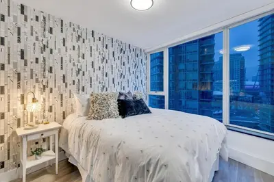 a bedroom with a bed and a large window at Modern 2BR 2BA Condo in Heart of Vancouver in Vancouver