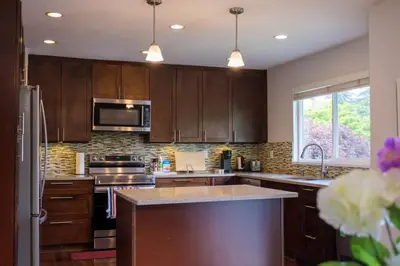 a kitchen with wooden cabinets and a counter top at Surrey Family Home w/ Patio & Garden – 3BR 2BA in Surrey