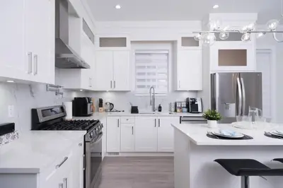 a white kitchen with white cabinets and stainless steel appliances at Modern 3BR Near Langley Events Centre & EV charger in Langley