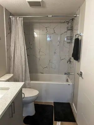 a bathroom with a toilet and a tub and a sink at Eli's Place in Calgary
