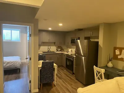 a small kitchen with a refrigerator and a table with chairs at stylish 5-Star Suite 1BD 1 Bath Le Reve Beaumont in Nisku