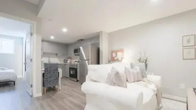 a white living room with a white couch and a kitchen at stylish 5-Star Suite 1BD 1 Bath Le Reve Beaumont in Nisku