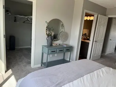 a bedroom with a bed and a table with a mirror at Le Reve Show Home 3BD, AC, sleep 9 , Beaumont in Nisku