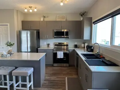 a kitchen with stainless steel appliances and a counter top at Le Reve Show Home 3BD, AC, sleep 9 , Beaumont in Nisku