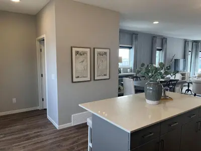 a kitchen and living room with a counter and a table at Le Reve Show Home 3BD, AC, sleep 9 , Beaumont in Nisku