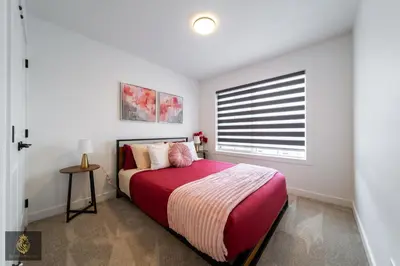 a bedroom with a bed with a red blanket and a window at FreshModernWEMGarageKingBed in Edmonton