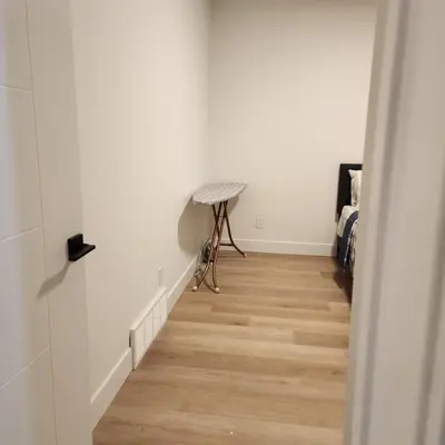a hallway with white walls and a wooden floor at Spacious 2 Bedroom Suite in Gorman, Edmonton, Canada in Edmonton