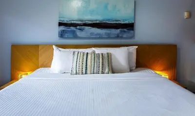 a bedroom with a white bed with a painting on the wall at Ha Ling Haven - Penthouse with Shared Rooftop Hot Tub in Canmore