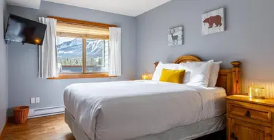 a bedroom with a large bed and a window at Ha Ling Haven - Penthouse with Shared Rooftop Hot Tub in Canmore