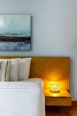 a bedroom with a white bed and a night stand with a candle at Ha Ling Haven - Penthouse with Shared Rooftop Hot Tub in Canmore