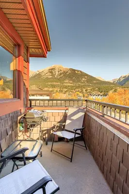 a balcony with chairs and tables and mountains in the background at Boardwalk Bliss - Top Floor Downtown Condo in Canmore