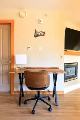 a desk with a chair with a lamp and a tv at Boardwalk Bliss - Top Floor Downtown Condo in Canmore