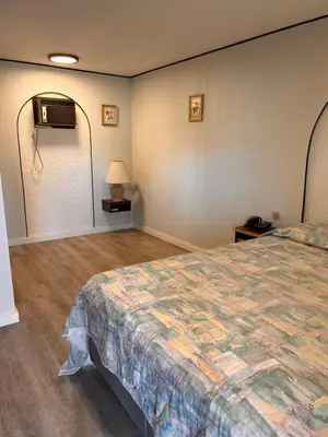 a bedroom with a large bed and a fan at Lakecity Inn in Penticton