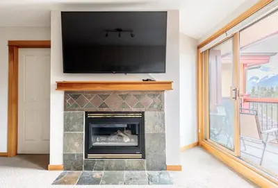 a living room with a fireplace with a flat screen tv at Mountainside - Stunning Views Downtown Location in Canmore
