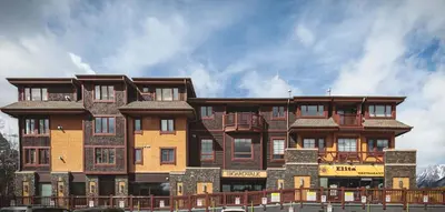 a large apartment building with a fence in front of it at Mountainside - Stunning Views Downtown Location in Canmore