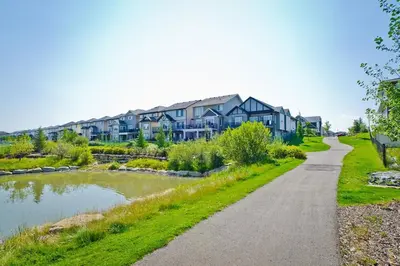 a road in front of a house next to a lake at The Vaulted Oasis 2-bedroom with a Garden in Airdrie