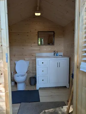a bathroom with a toilet and a sink and a mirror at Creekside Bunkies in Roberts Creek