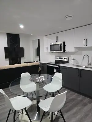 a kitchen with a glass table and white chairs at 2 bedroom cozy suite in NW edmonton with separate entrance, FreeWifi, driveway Parking, Netflix, AC, airport pickup in Edmonton