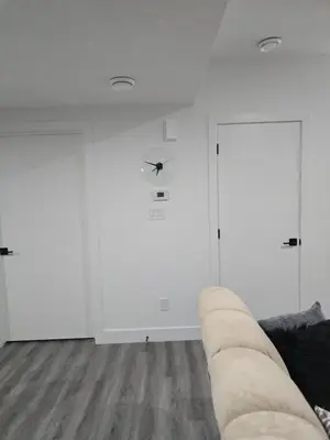 a living room with white walls and a couch at 2 bedroom cozy suite in NW edmonton with separate entrance, FreeWifi, driveway Parking, Netflix, AC, airport pickup in Edmonton