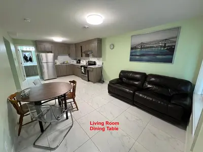 a living room with a leather couch and a dining room table at Newton Suite in Surrey