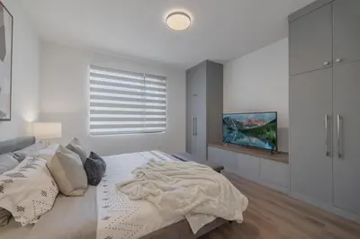 a white bedroom with a bed and a tv at Fenced Yard, Free Parking, 2 King Beds with AC in Calgary