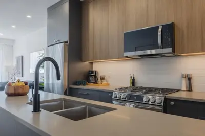 a kitchen with a sink and a stove top oven at Fenced Yard, Free Parking, 2 King Beds with AC in Calgary