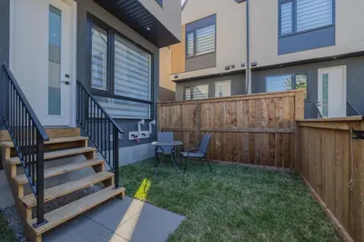 a small backyard with a wooden fence and stairs at Fenced Yard, Free Parking, 2 King Beds with AC in Calgary