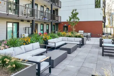 a patio with couches and tables and flowers at Brand new suite downtown Kelowna - walk everywhere! in Kelowna