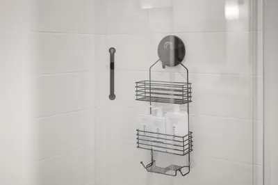 a shower rack with bottles and a shower head at Chic Condo with Stylish Amenities in White Rock in Surrey