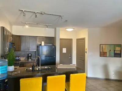 a kitchen with a sink and yellow chairs in it at PlayadelSol in Kelowna