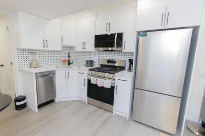 a kitchen with white cabinets and a white refrigerator at Cozy Quarters Your Comfy Haven in Calgary
